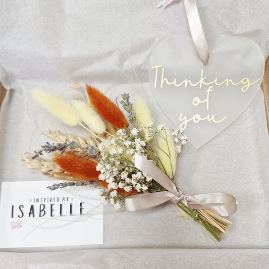 Bouquet of dried flowers with a ribbon on a textured surface, featuring the text 'Thinking of you' and 'Inspired by Isabelle'.